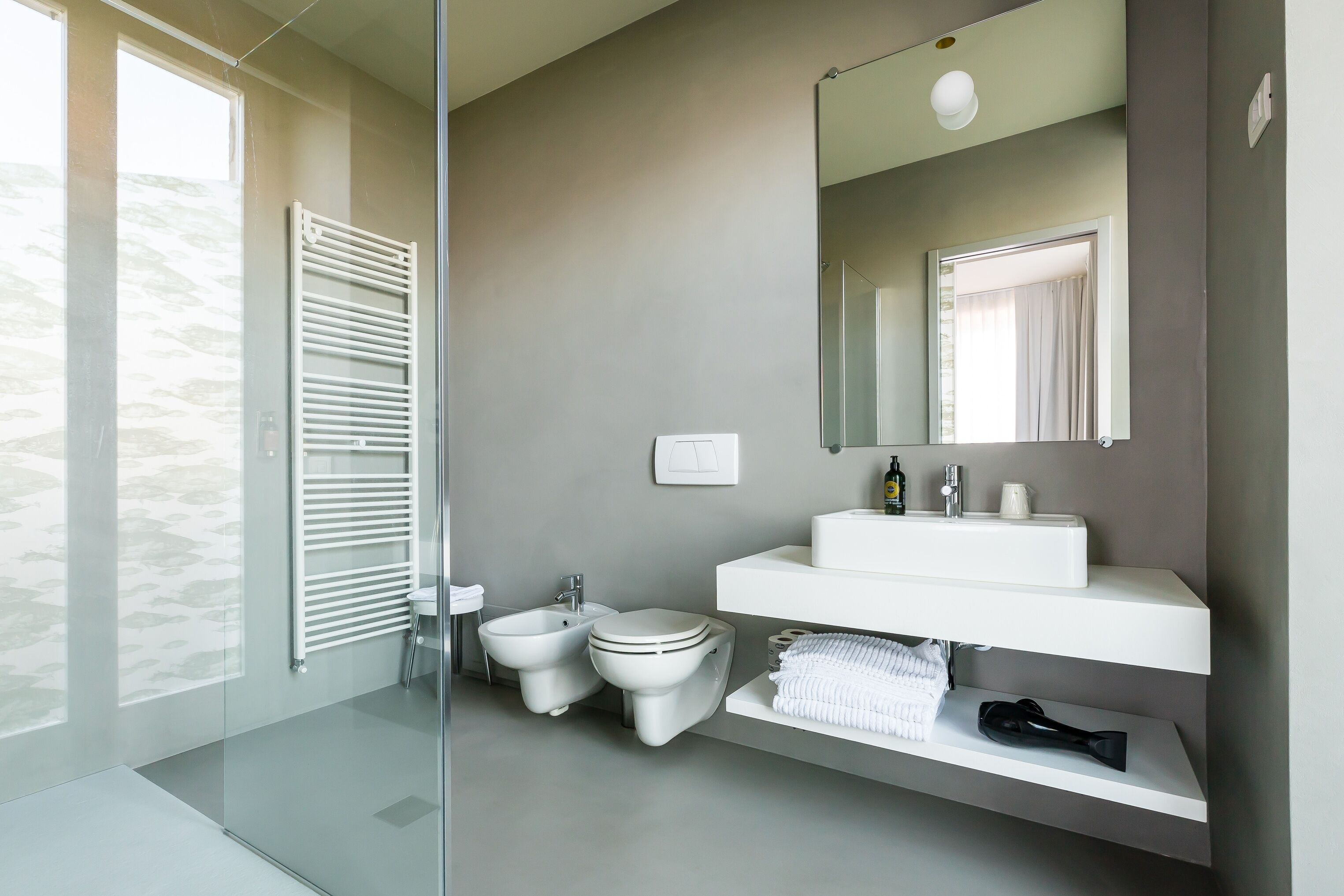 Un baño moderno con cabina de ducha de vidrio, un lavamanos blanco, un bidé y un espejo grande.