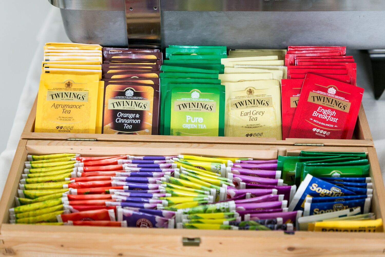 Una caja de madera con varias bolsitas y paquetes de té Twinings.