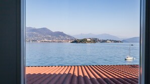 A view of a lake with a boat, mountains, and a distant shoreline. - Hotel Belvedere (Stresa)