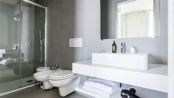 A modern bathroom with a glass shower enclosure, a white sink with a mirror above, and a toilet.