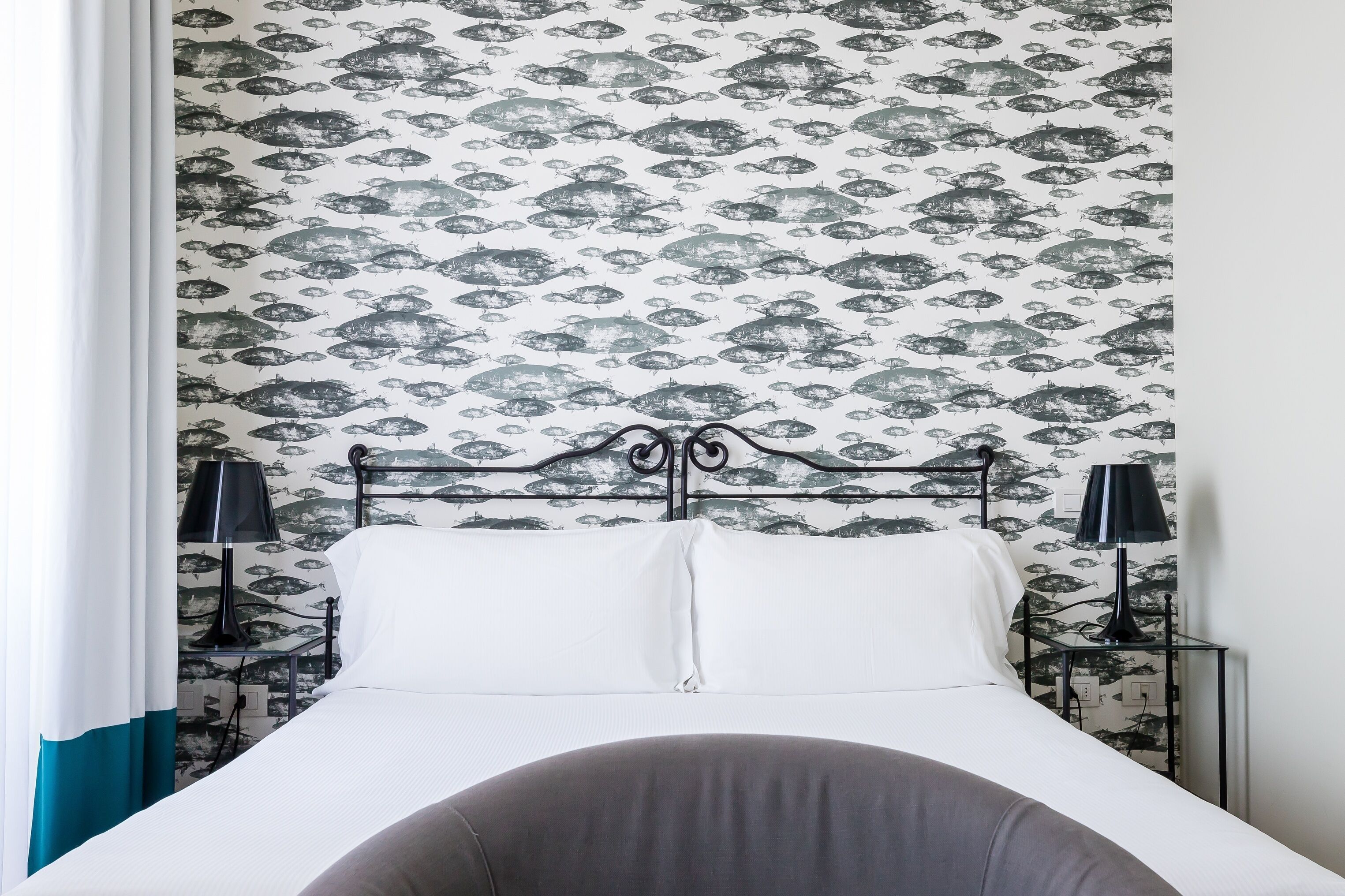 A bed with white linens, a black metal headboard, and two bedside tables with black lamps.