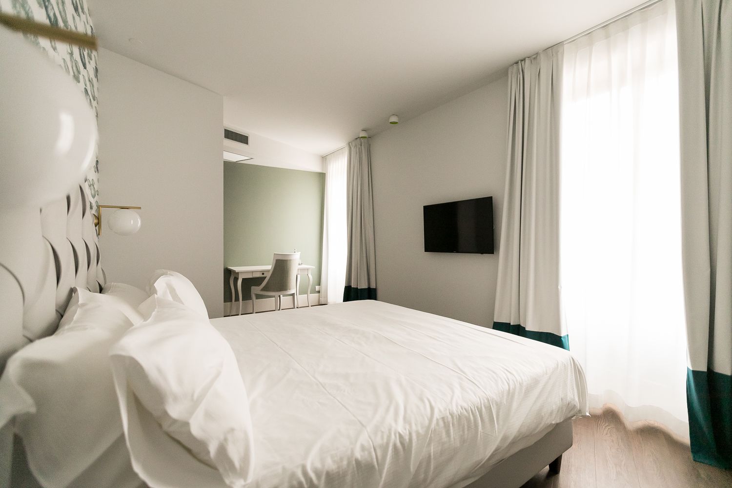 Una habitación de hotel con una cama grande, un escritorio y un televisor.
