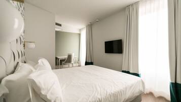 Una habitación de hotel con una cama grande, un escritorio y un televisor.