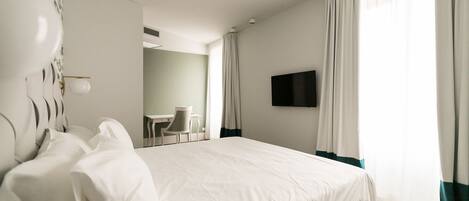 A hotel room with a large bed, a desk, and a television.