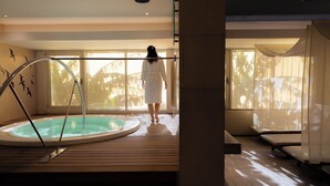 Un área de spa con jacuzzi, suelo de madera y ventanas amplias que dejan entrar luz natural.