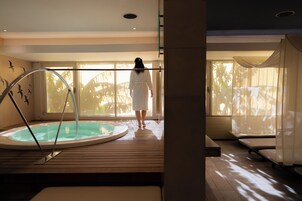Un área de spa con jacuzzi, suelo de madera y ventanas amplias que dejan entrar luz natural.