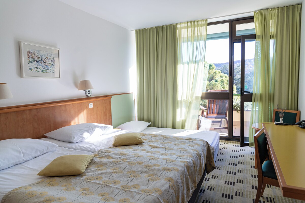 Ein Hotelzimmer mit Bett, Schreibtisch und Blick ins Freie.
