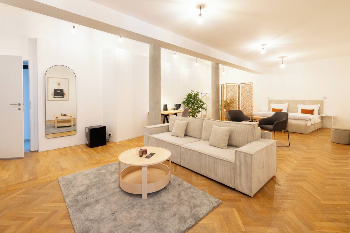A spacious living area with a sofa, coffee table, and a large mirror.