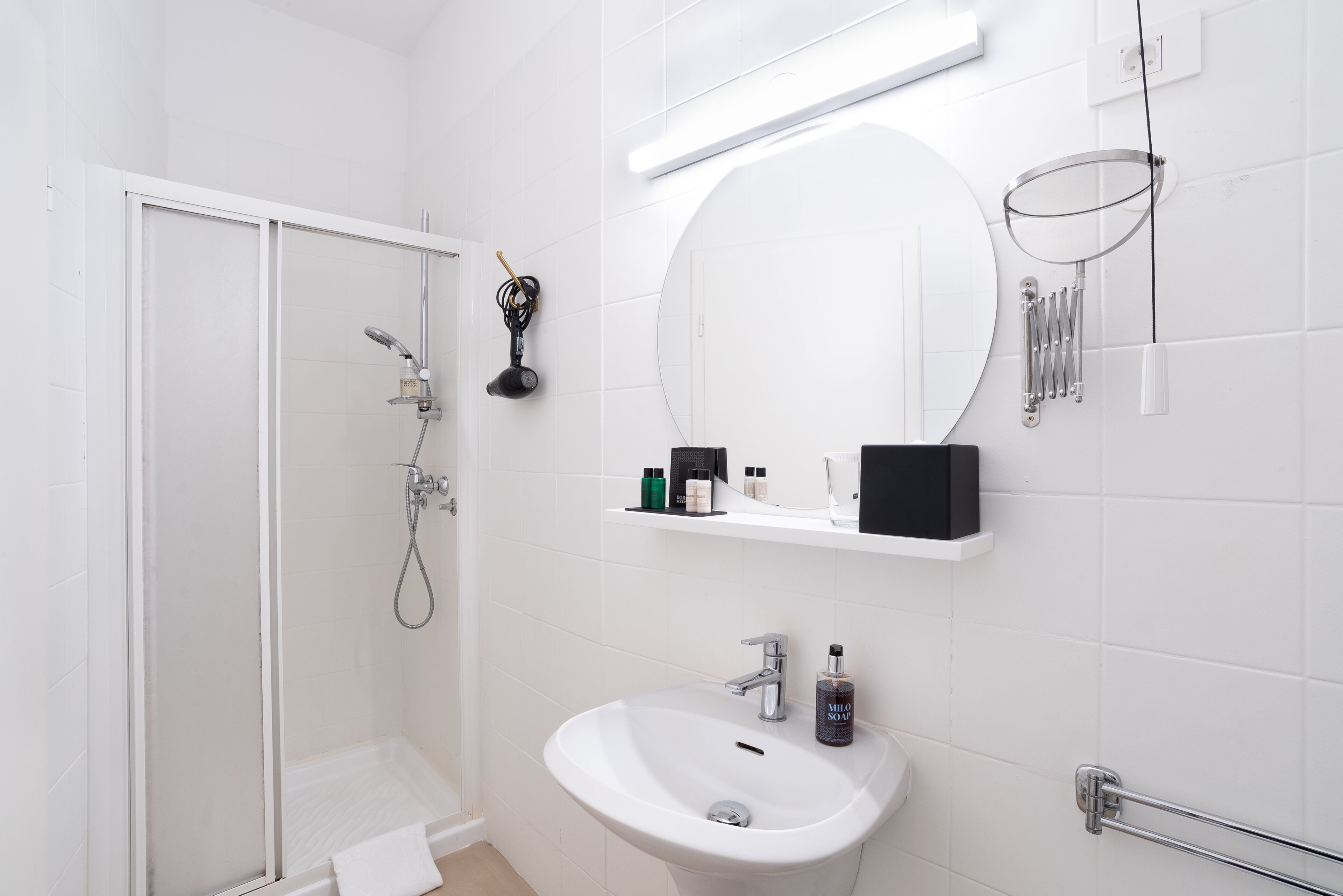 Ein modernes Badezimmer mit einer Duschkabine aus Glas, einem weißen Waschbecken und einem Spiegel darüber.