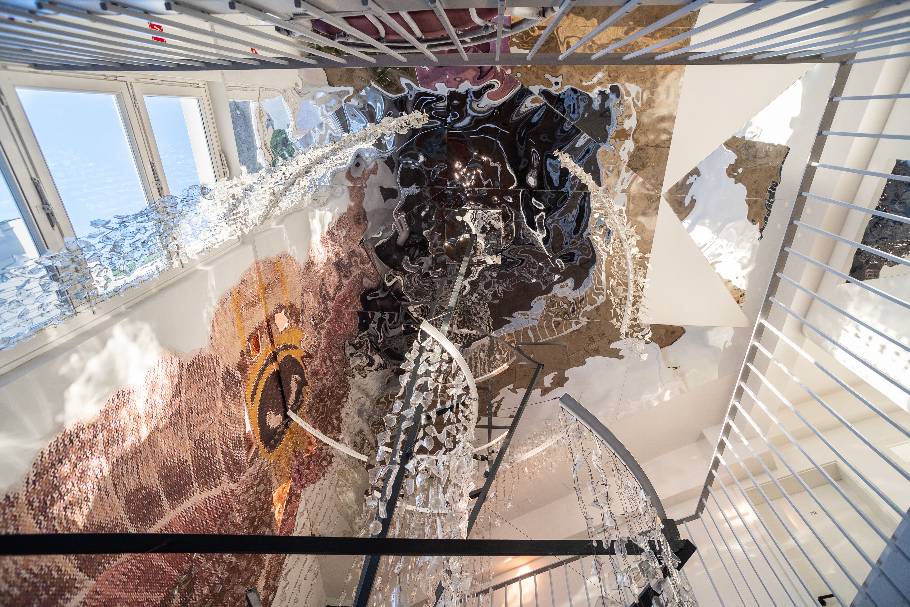 A modern interior with a high ceiling, reflective surfaces, and a central spiral staircase.