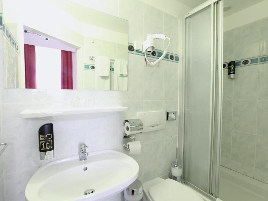 Un baño moderno con lavamanos, inodoro y cabina de ducha de vidrio.