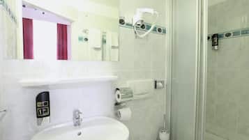 Un baño moderno con lavamanos, inodoro y cabina de ducha de vidrio.