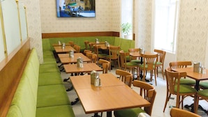 A restaurant with green cushioned benches, wooden tables, and chairs. - Hotel Pension Andreas (Vienna)