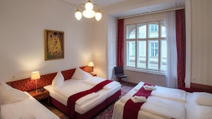 A hotel room with two beds, a large window with curtains, a painting on the wall, and a desk with a chair. - Hotel Pension Andreas (Vienna)