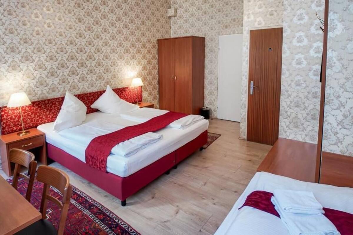 Quarto de hotel com cama, escrivaninha, guarda-roupa e porta.