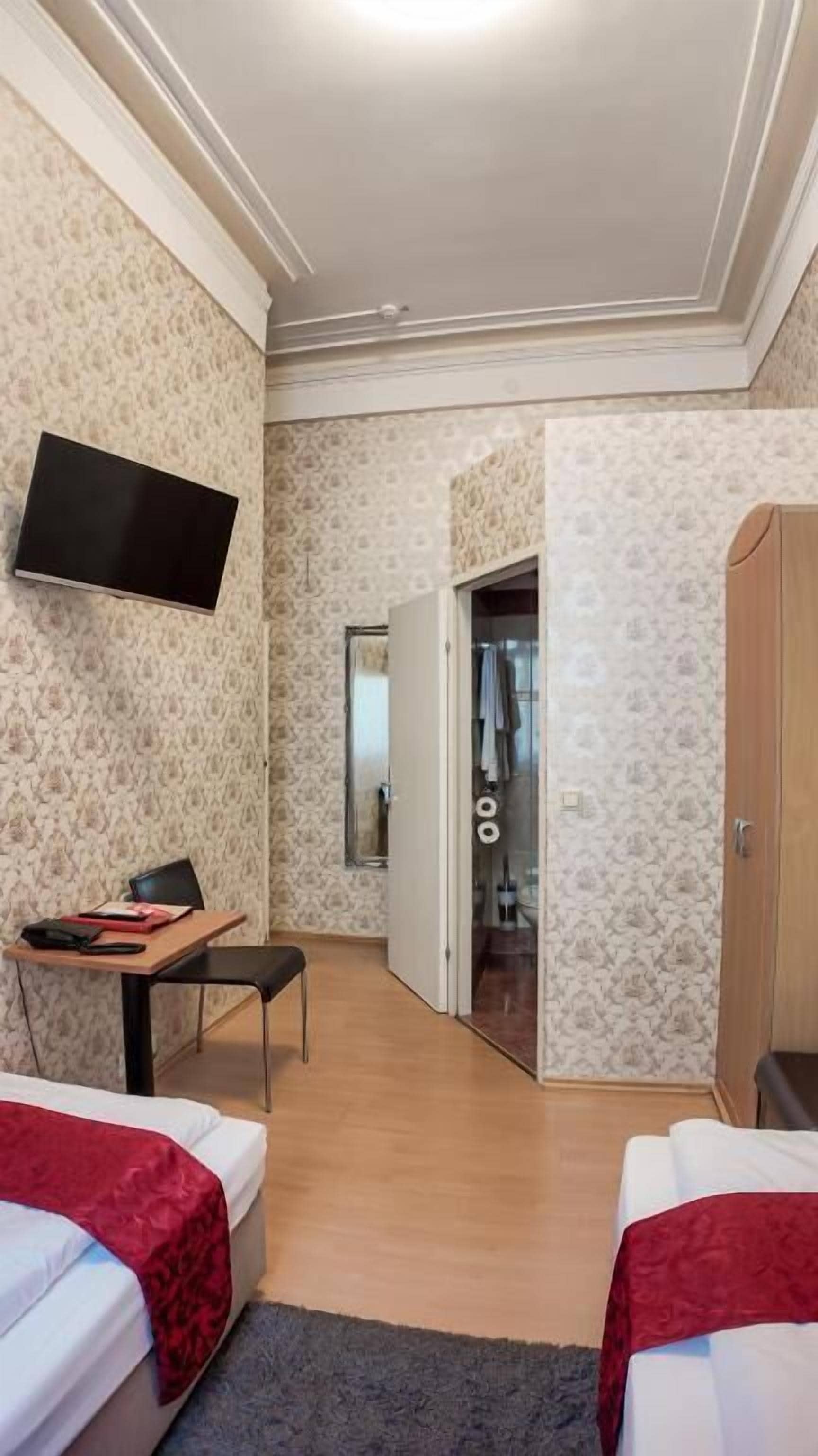 Una habitación de hotel con dos camas, un escritorio con una silla, un televisor y un armario.