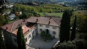 A villa with a courtyard, surrounded by trees and a view of rolling hills and distant buildings. - Villa Ducci (San Gimignano)