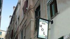 Een smalle straat met een gebouw, waarop een bord staat met de tekst 