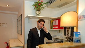 Een hotel receptie met een marmeren balie, een telefoon, een lamp en een plant aan de muur.