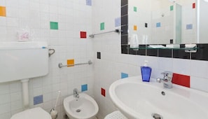 A bathroom with a toilet, bidet, sink, and mirror. - Rainbow (Palermo)