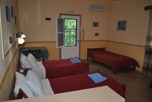 A room with two beds, a desk, and a door with a window. - Stelios Studios (Skiathos)
