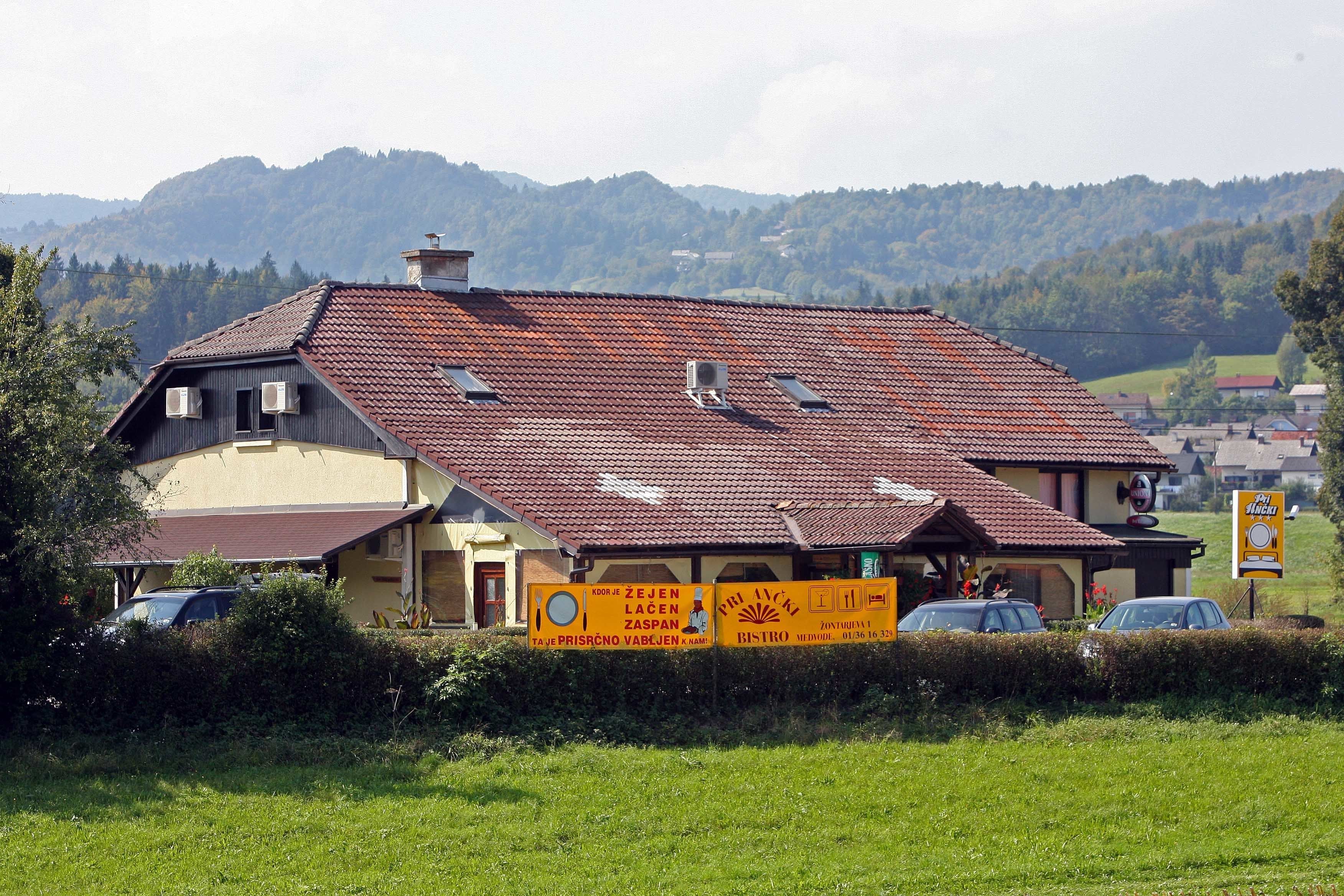 Un edificio con techo de tejas rojas, un cartel de restaurante y vistas a montañas al fondo.