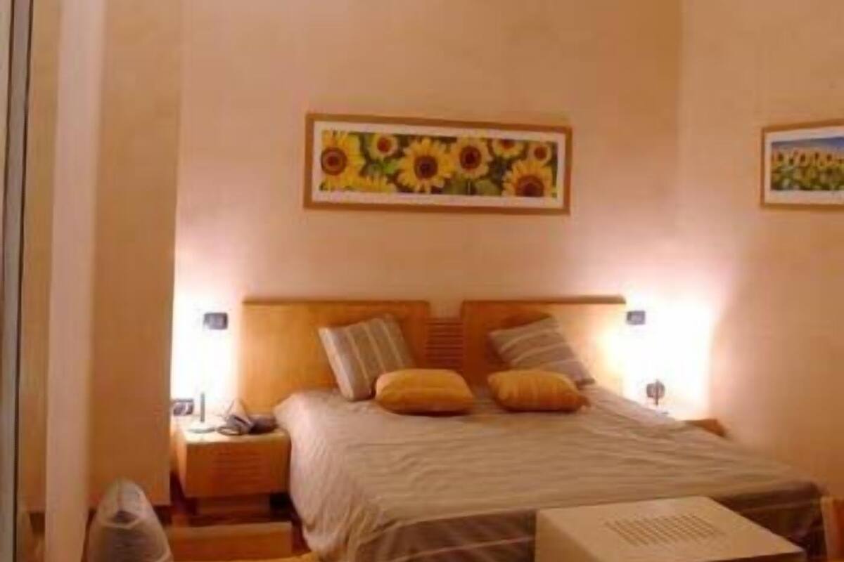 A bedroom with a bed, bedside tables, a nightstand, a chair, and a desk.