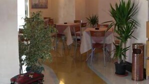 Un comedor con mesas, sillas y plantas en macetas.
