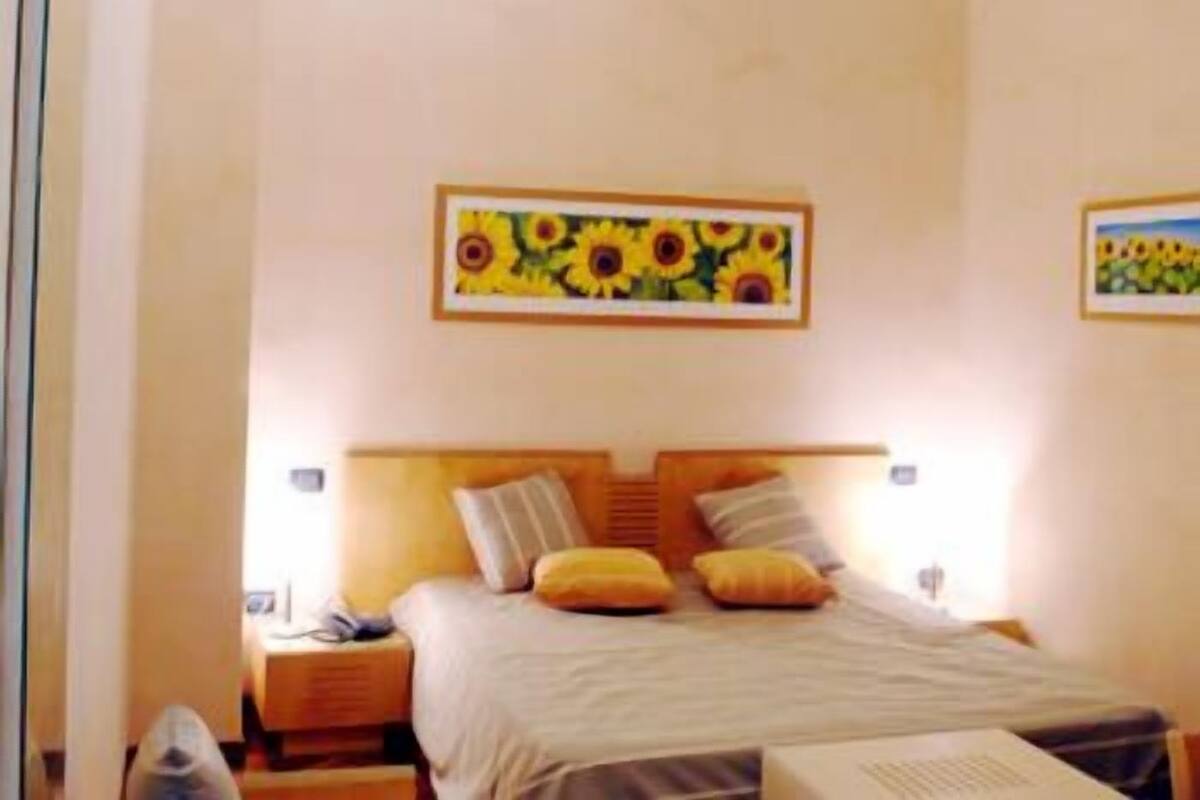 A bedroom with a bed, pillows, a nightstand, and two framed pictures on the wall.