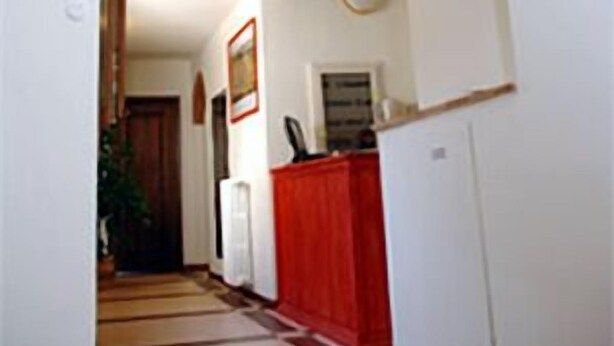 A hallway with a brick archway, white walls, and a red cabinet. - Arco Antico (Florence)