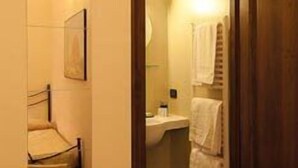 A hotel bathroom with a wooden door, a sink, a mirror, and a towel rack. - Arco Antico (Florence)