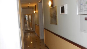 A hotel hallway with a tiled floor, a framed map on the wall, and a door at the end. - Hotel Pension Stadtpark (Vienna)