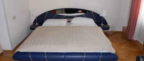 A bed with a blue headboard and footboard, white bedding, and two bedside lamps.