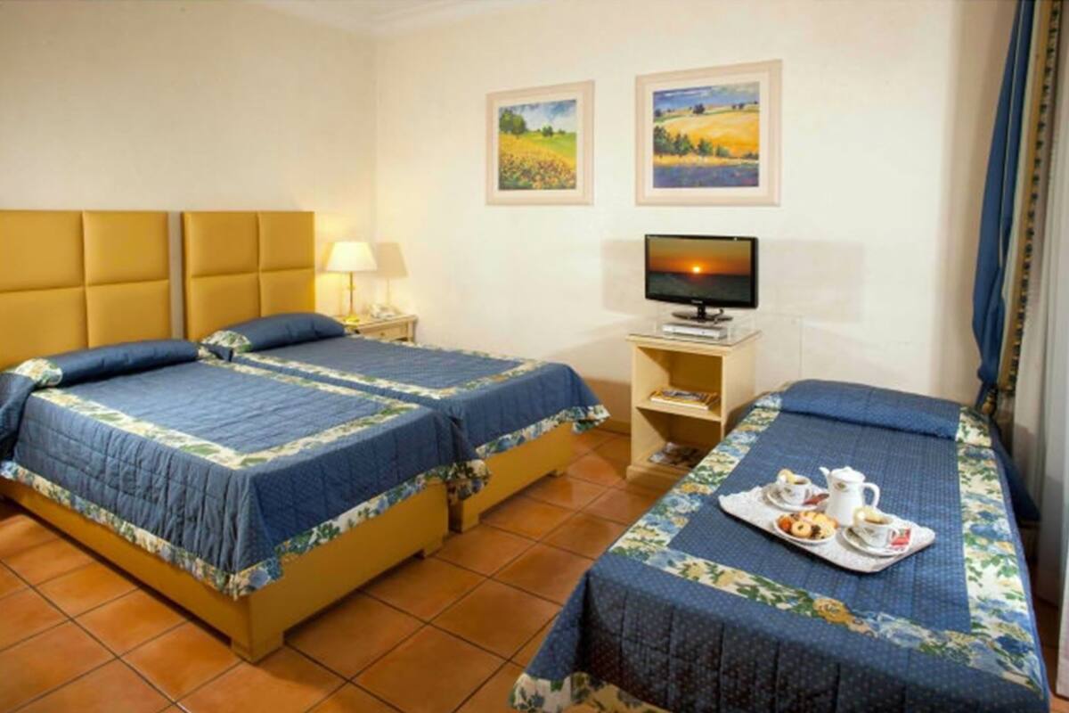 A hotel room with two beds, a television, and a tray with breakfast items.