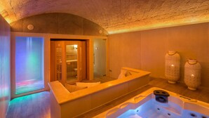 Une salle de spa équipée d’un bain à remous, d’un grand miroir et de deux vases décoratifs.