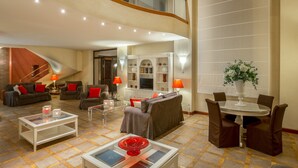 Un vaste espace de vie doté d’un haut plafond, d’un escalier et d’un coin repas avec une table ronde et des chaises.