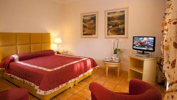Una camera d'albergo con un letto, una televisione, una sedia e un piccolo tavolo con una lampada.