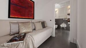 Un salon moderne avec un canapé beige, un tableau abstrait rouge et un magazine posé sur le canapé.