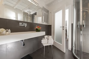 Un baño moderno con un espejo grande, un perchero para toallas y una zona de ducha.