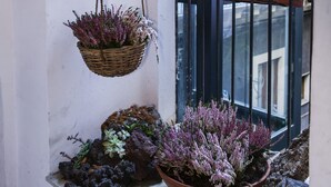 Un balcon agrémenté de plantes en pot et d’une jardinière suspendue.