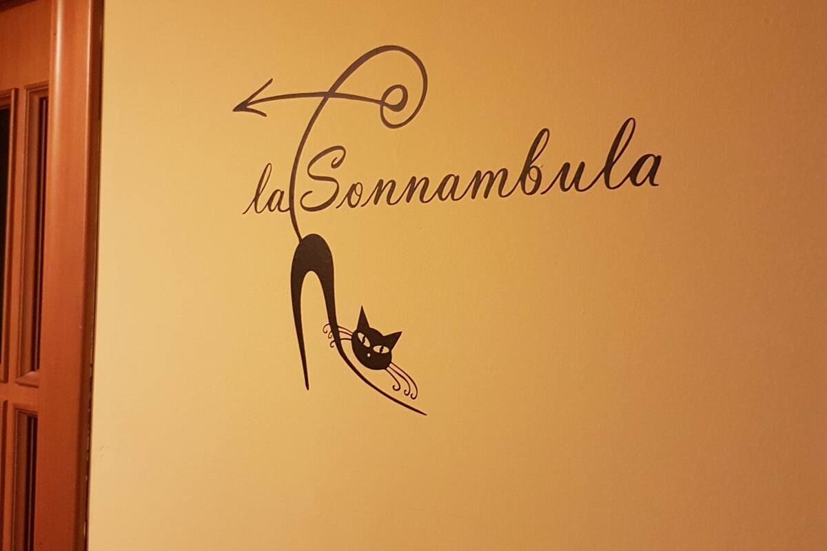 Un muro con la scritta “la Sonnambula” e un’illustrazione di un gatto nero.