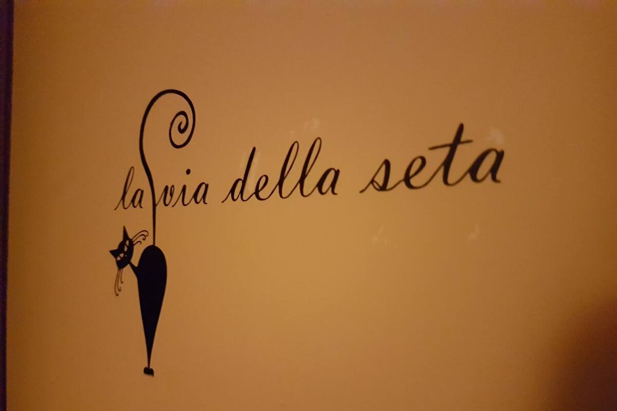 Un muro con la scritta 'la via della seta' e la sagoma di un gatto.
