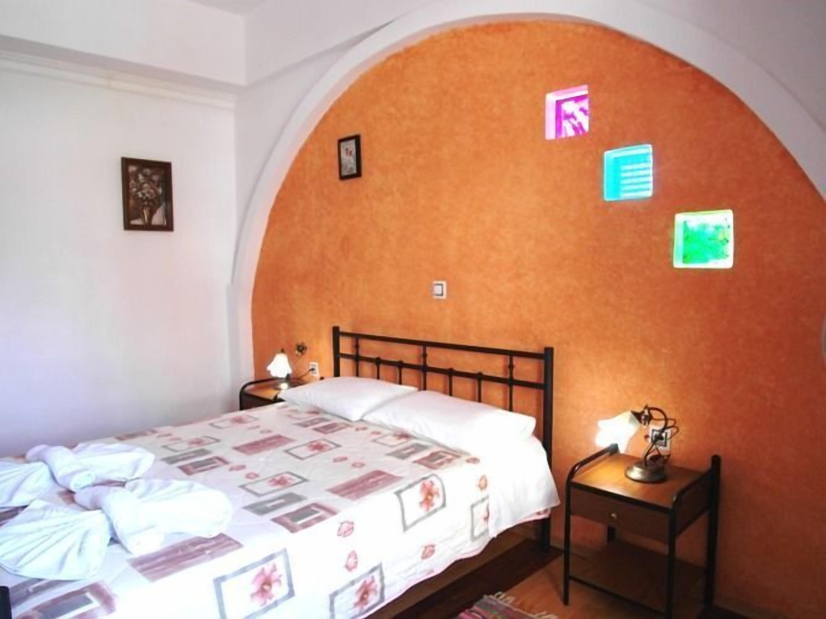 A bedroom with a bed, a nightstand, and a wall with pictures.