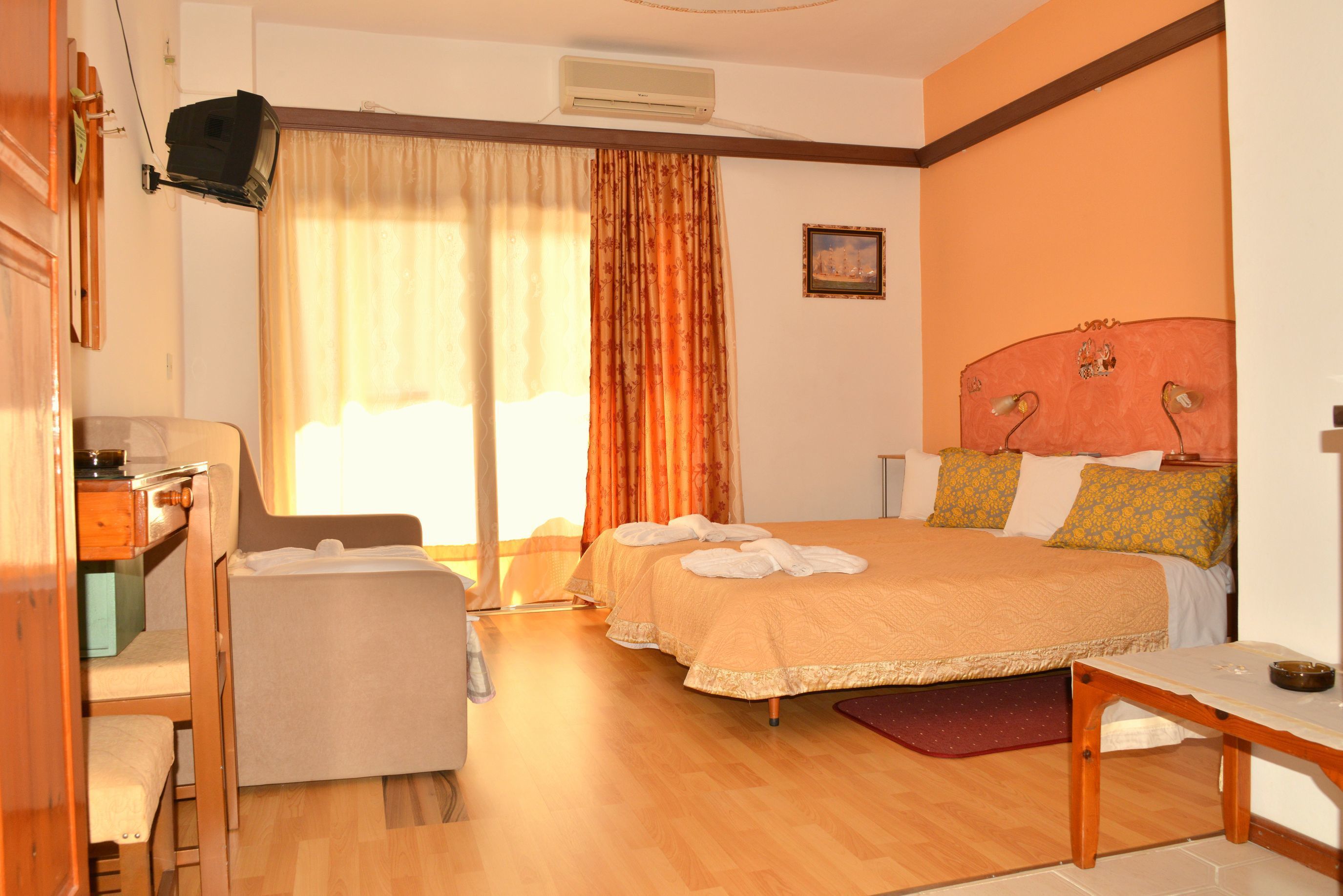 A hotel room with two beds, a desk, a chair, and a TV.