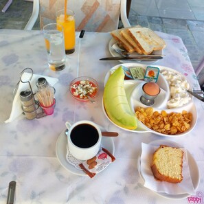 Una mesa servida con artículos de desayuno, como tostadas, fruta, cereal y café.