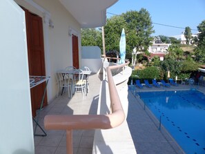 Zona de piscina con mesa y sillas, piscina y vistas del barrio circundante.