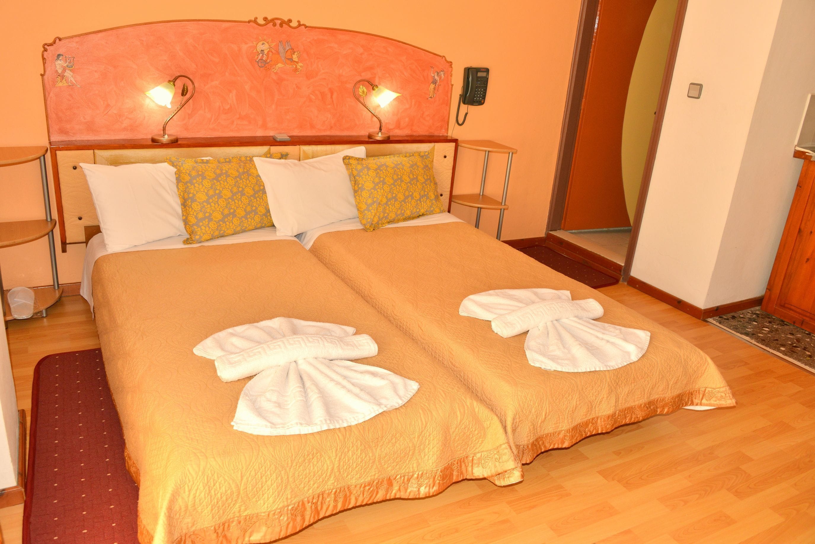 Ein Doppelbett mit zwei Kissen, ein Nachttisch, ein Telefon an der Wand.