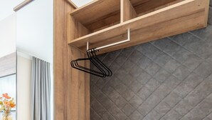 A modern room with a wooden partition, a grey cushioned bench, and a hanging rack. - Das Jedermann Boutiquehotel (Salzburg)