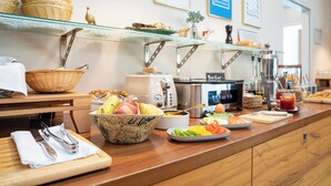 A breakfast buffet with various food items, a coffee machine, and a toaster. - Das Jedermann Boutiquehotel (Salzburg)