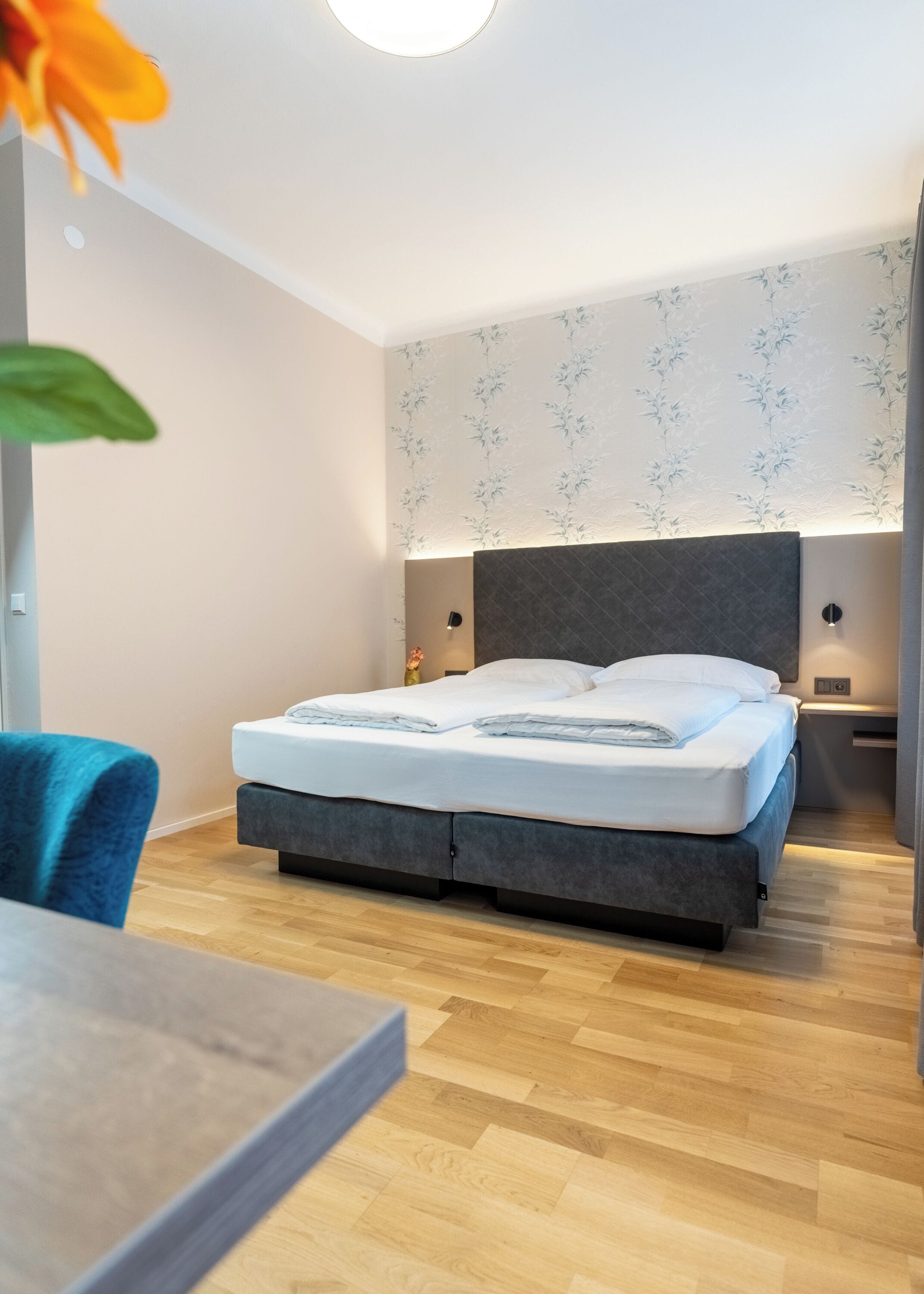 A modern bedroom with a bed, bedside tables, a desk, and a chair.
